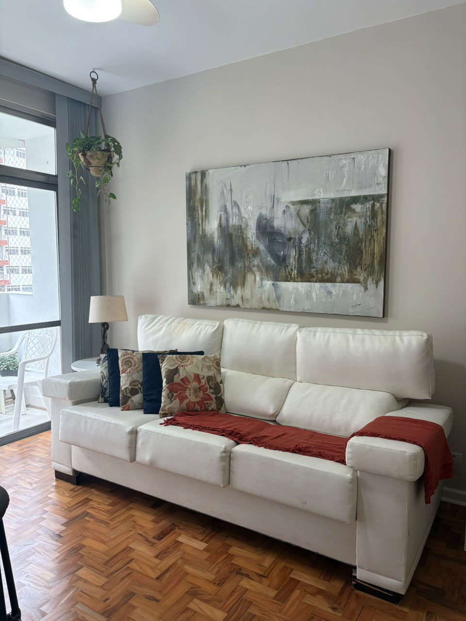 Sala da Casa Pitanga, com sofá e plantas junto à varanda